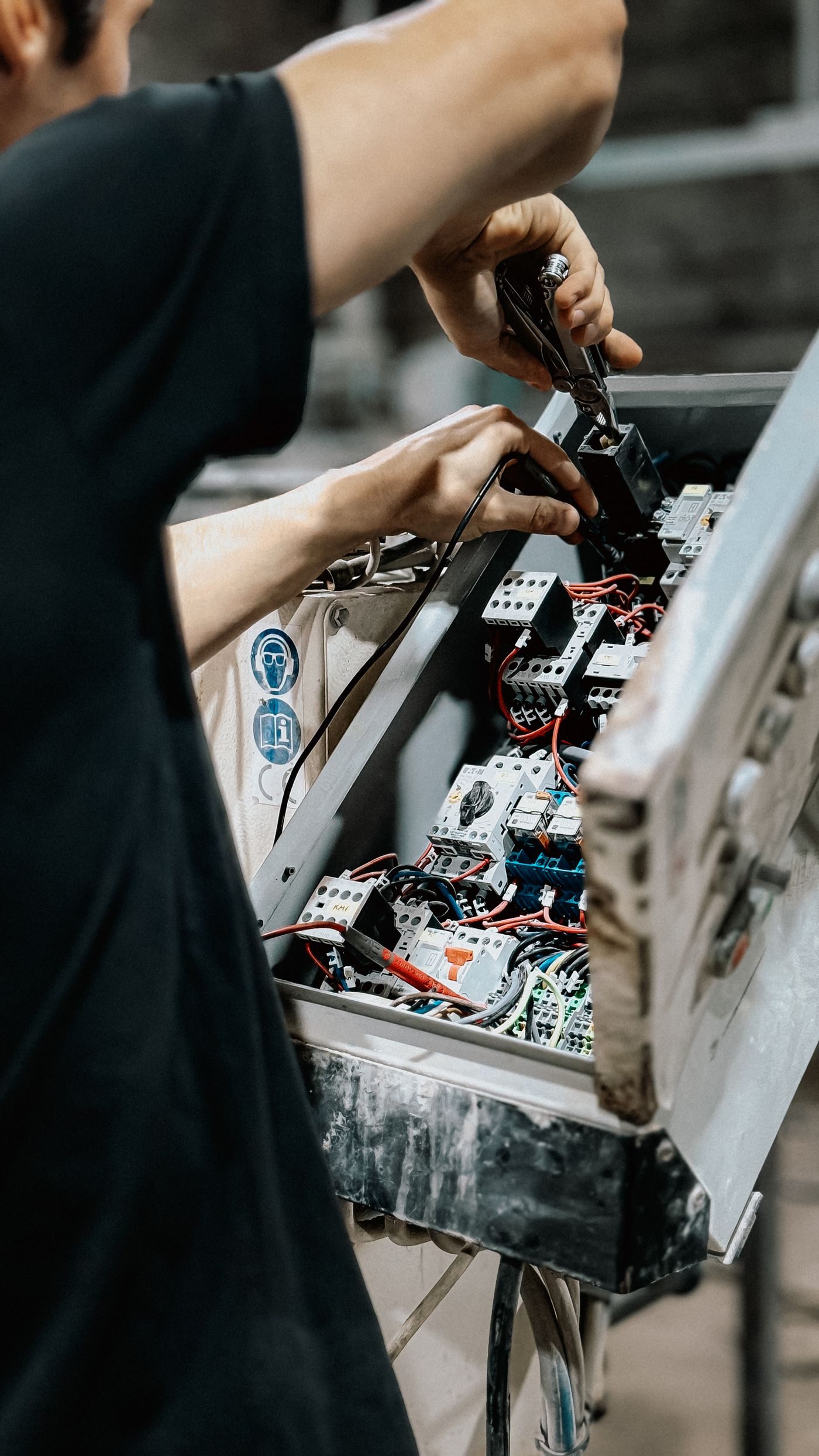Electrician working on breakers and wiring inside an open distribution board